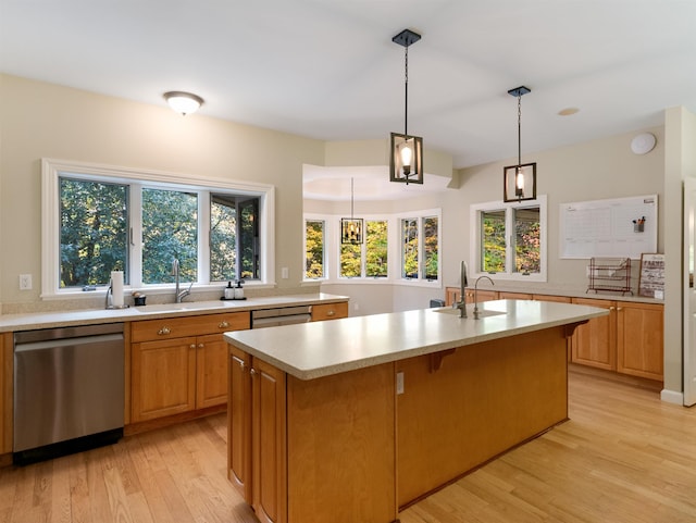 kitchen with dishwasher, light wood-type flooring, a kitchen island with sink, and sink