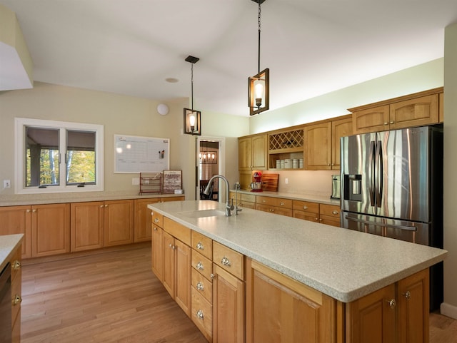 kitchen featuring stainless steel fridge, a center island with sink, and light hardwood / wood-style flooring