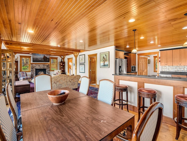 dining area with a fireplace, wood ceiling, and light hardwood / wood-style floors