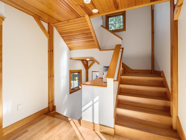 stairway featuring vaulted ceiling, wood ceiling, and hardwood / wood-style floors