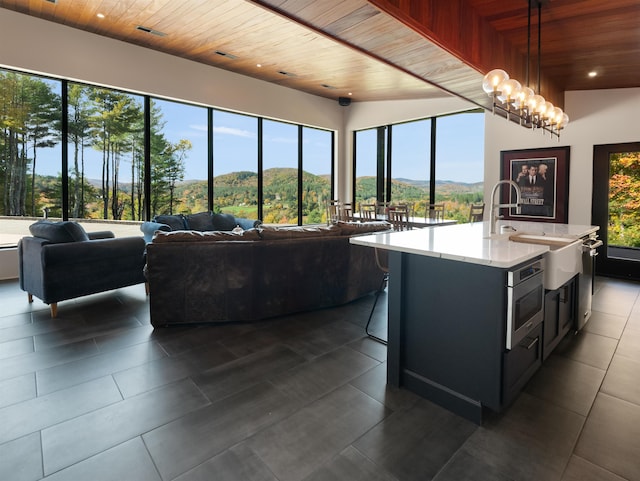 kitchen with pendant lighting, a center island with sink, wooden ceiling, and a wealth of natural light