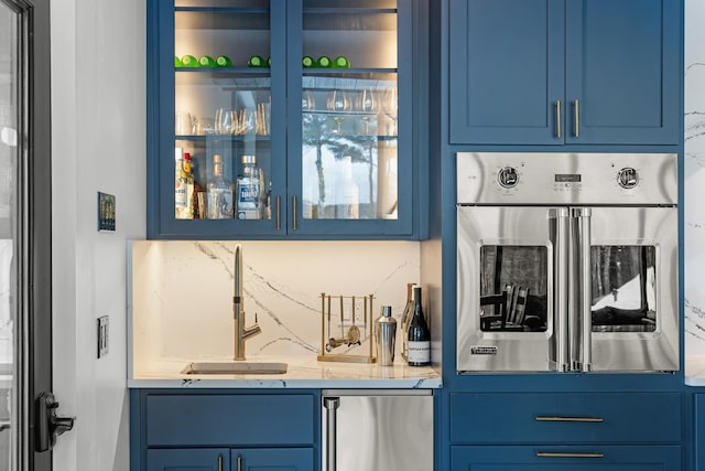 bar featuring blue cabinetry and appliances with stainless steel finishes