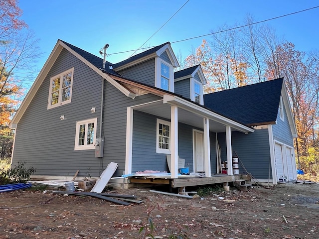 back of property with covered porch and a garage