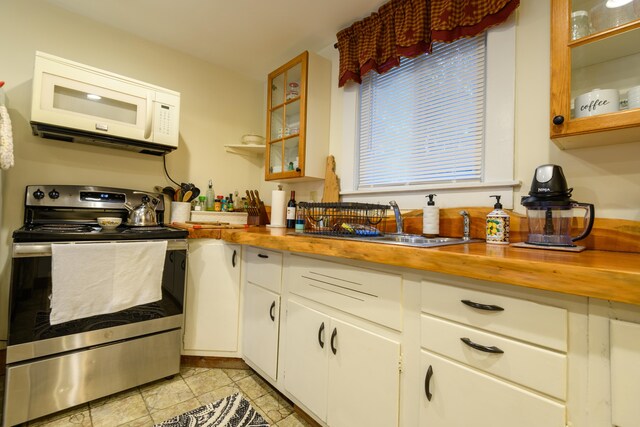 kitchen with wood counters, stainless steel range with electric cooktop, sink, and white cabinets