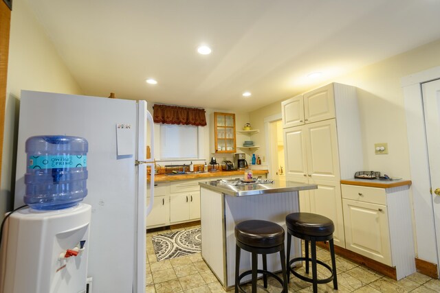 kitchen with a center island, white cabinets, sink, a breakfast bar area, and white refrigerator