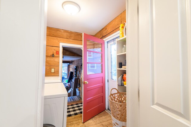 clothes washing area featuring separate washer and dryer and wooden walls