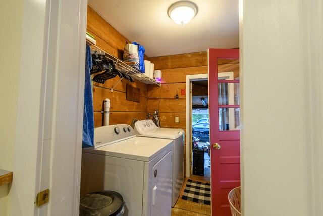 clothes washing area with wooden walls and washing machine and clothes dryer