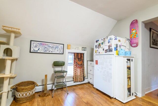 kitchen with white refrigerator, hardwood / wood-style floors, vaulted ceiling, and a baseboard radiator