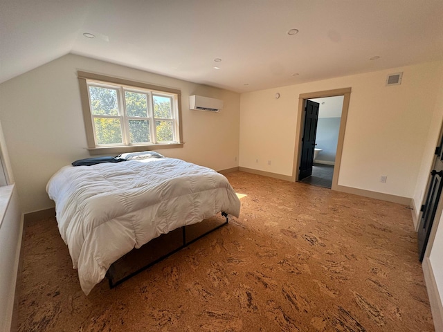 carpeted bedroom with a wall mounted AC, vaulted ceiling, and ensuite bath