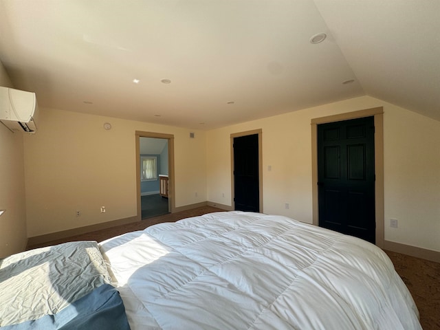 carpeted bedroom with lofted ceiling, ensuite bathroom, and a wall unit AC