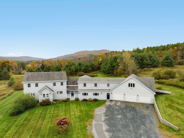 view of front of home featuring a garage, a mountain view, and a front lawn