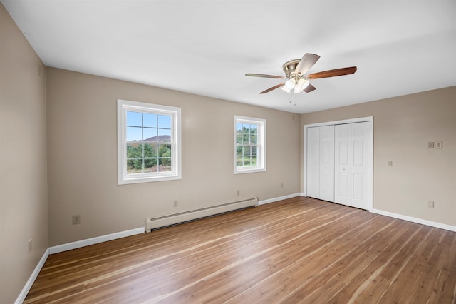 unfurnished bedroom featuring hardwood / wood-style flooring, ceiling fan, a closet, and a baseboard heating unit