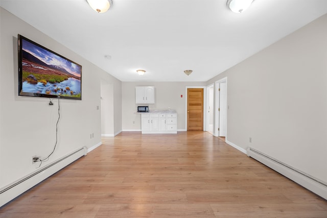 unfurnished living room featuring light hardwood / wood-style flooring and a baseboard heating unit