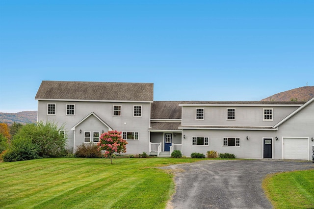 view of front of home featuring a garage, a mountain view, and a front lawn