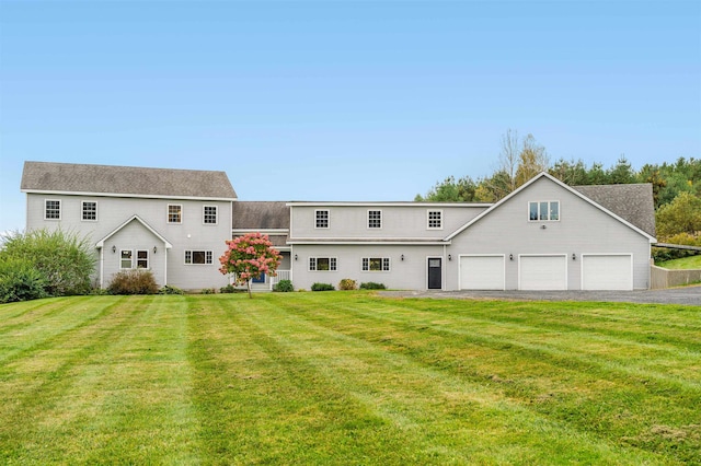 rear view of house featuring a garage and a yard