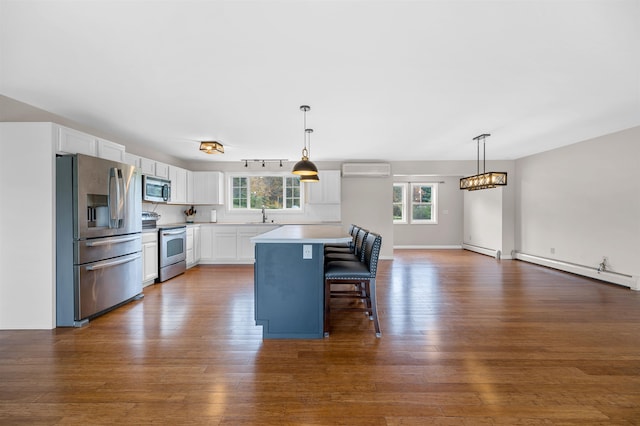 kitchen with white cabinets, appliances with stainless steel finishes, a kitchen island, and a wealth of natural light