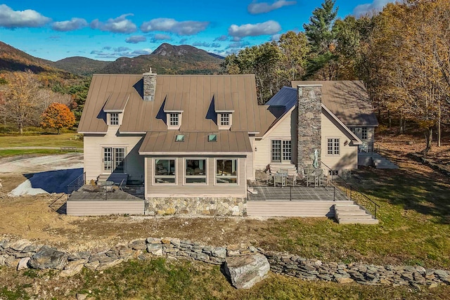 back of house featuring a deck with mountain view, a lawn, and a patio area