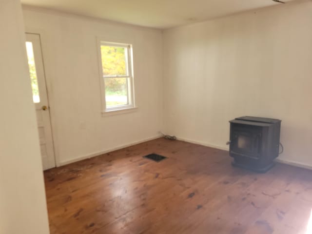 empty room with a wood stove and dark hardwood / wood-style flooring