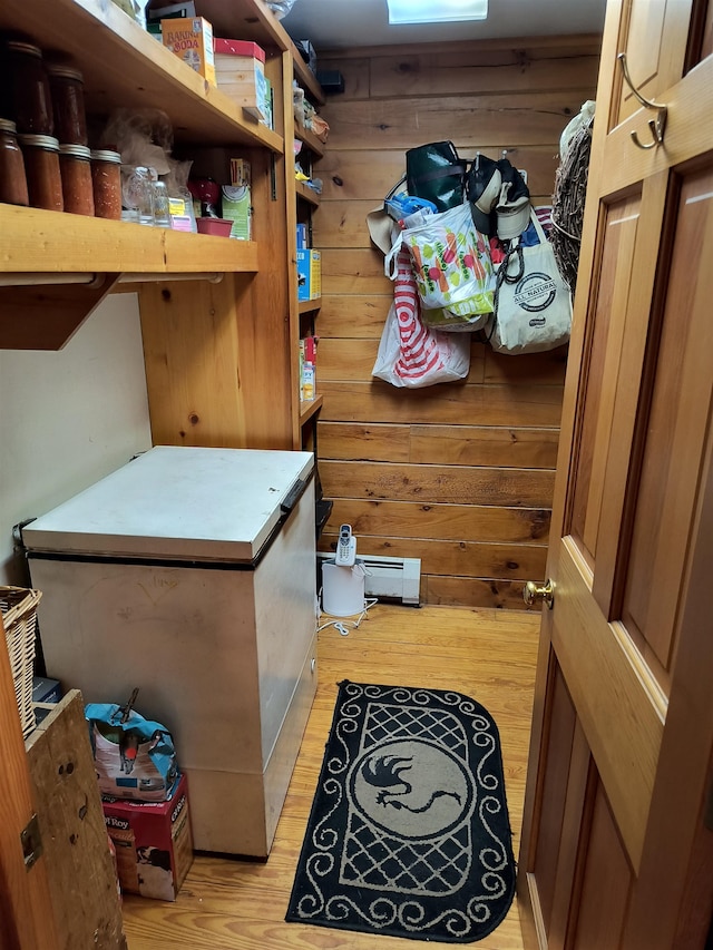 clothes washing area with wood walls, washing machine and dryer, and light hardwood / wood-style flooring