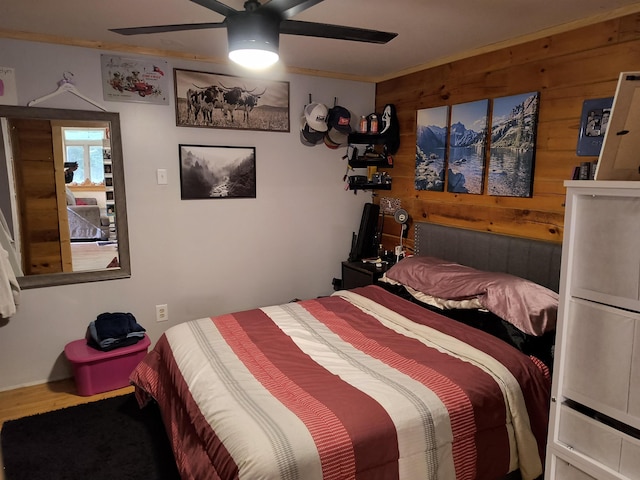 bedroom featuring ceiling fan, wooden walls, crown molding, and hardwood / wood-style floors