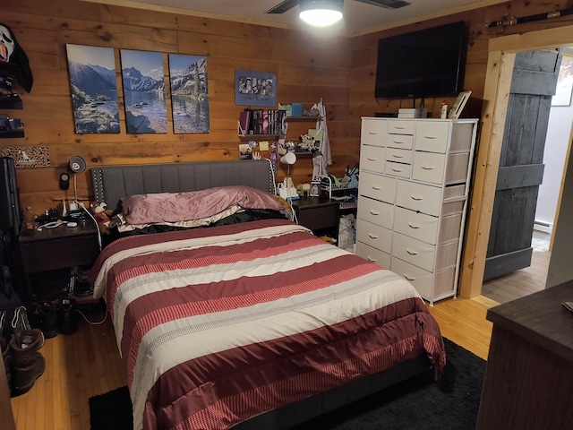 bedroom with wooden walls, ceiling fan, and hardwood / wood-style floors