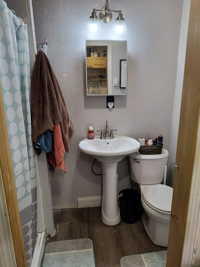 bathroom with hardwood / wood-style flooring, toilet, and a shower with curtain