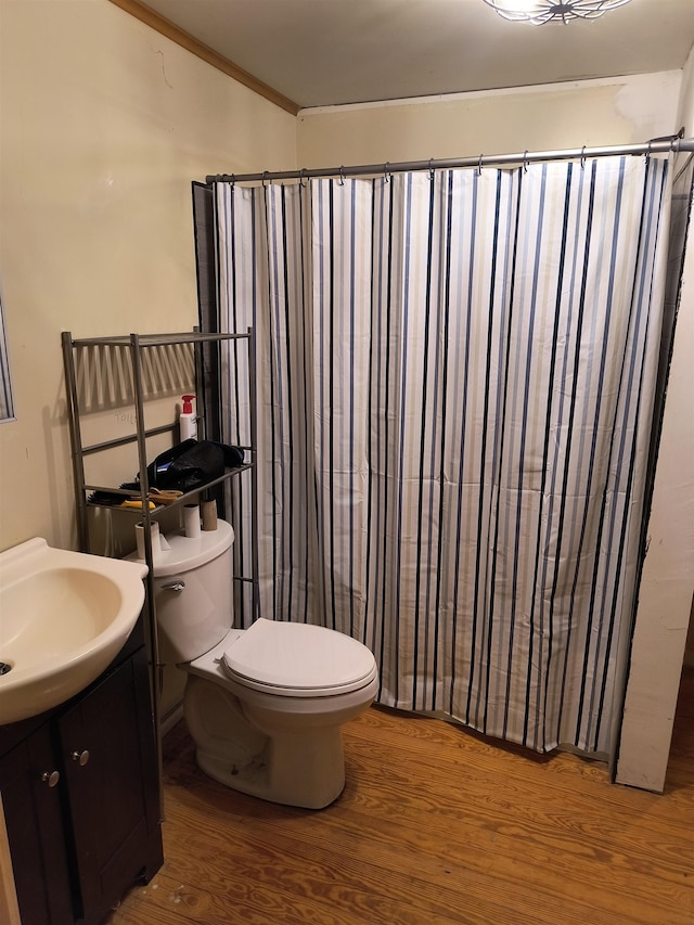 bathroom with hardwood / wood-style floors, vanity, walk in shower, crown molding, and toilet