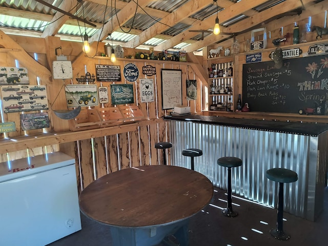 bar featuring white refrigerator and vaulted ceiling with skylight