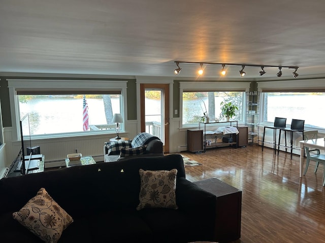 living room featuring rail lighting, a baseboard heating unit, and hardwood / wood-style flooring