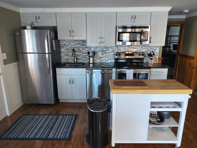 kitchen with ornamental molding, stainless steel appliances, sink, butcher block countertops, and dark hardwood / wood-style floors