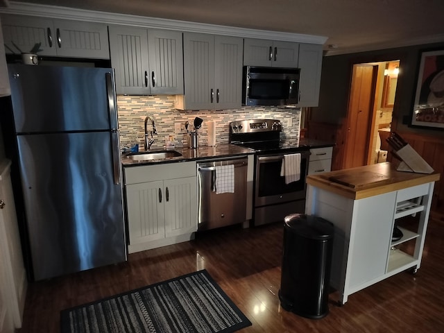 kitchen featuring appliances with stainless steel finishes, tasteful backsplash, dark wood-type flooring, sink, and butcher block counters