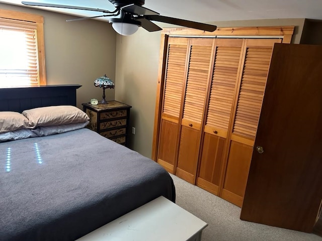 carpeted bedroom featuring ceiling fan and a closet