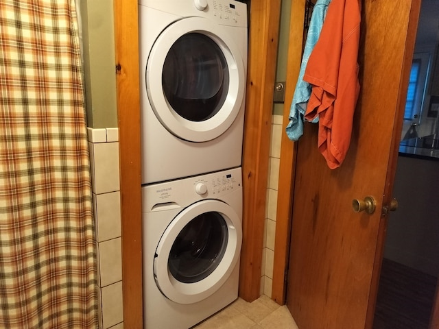 laundry room with stacked washer and dryer and light tile patterned flooring