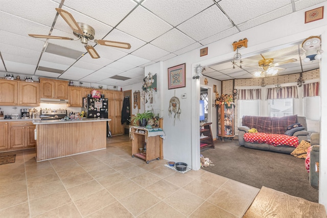 kitchen featuring a drop ceiling, black refrigerator, stainless steel range with electric cooktop, a kitchen island, and light tile patterned floors