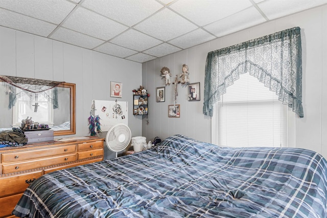 bedroom with wooden walls and a drop ceiling