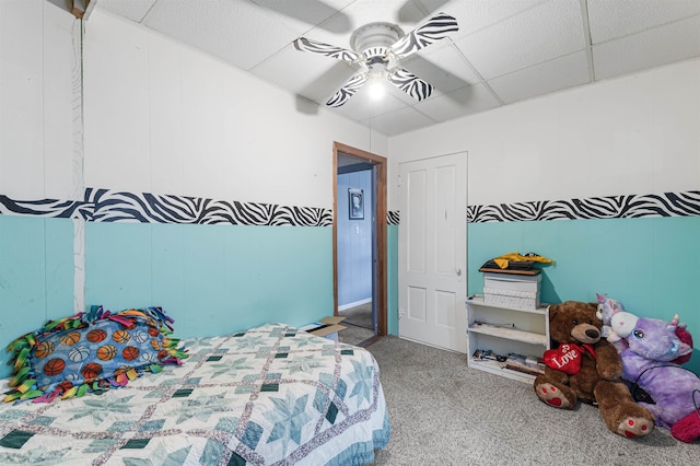 carpeted bedroom with a paneled ceiling and ceiling fan