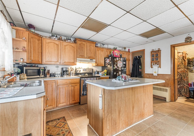 kitchen featuring radiator, sink, a kitchen island, stainless steel appliances, and a drop ceiling