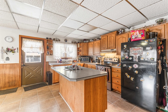 kitchen featuring appliances with stainless steel finishes, a drop ceiling, a center island, and light tile patterned floors