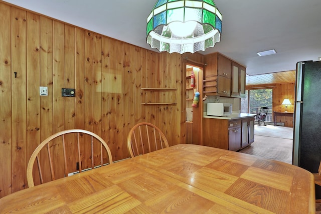 unfurnished dining area with wood walls and light colored carpet