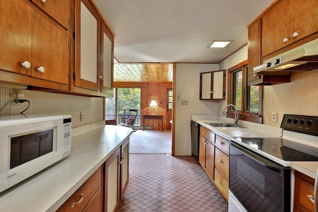 kitchen featuring wood walls, white appliances, sink, and light carpet