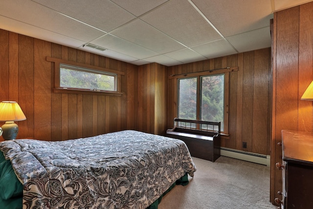 bedroom with a paneled ceiling, a baseboard radiator, wood walls, and carpet flooring