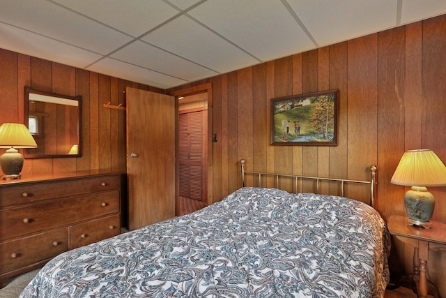 bedroom featuring wooden walls, a closet, and carpet flooring