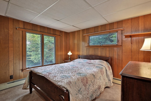 bedroom with light carpet, a baseboard radiator, a paneled ceiling, and wood walls