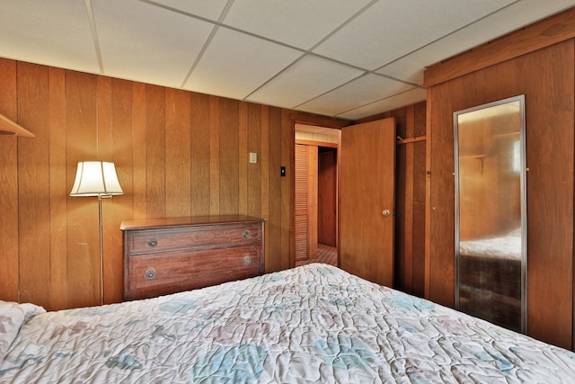 unfurnished bedroom with wood walls, a closet, and a paneled ceiling