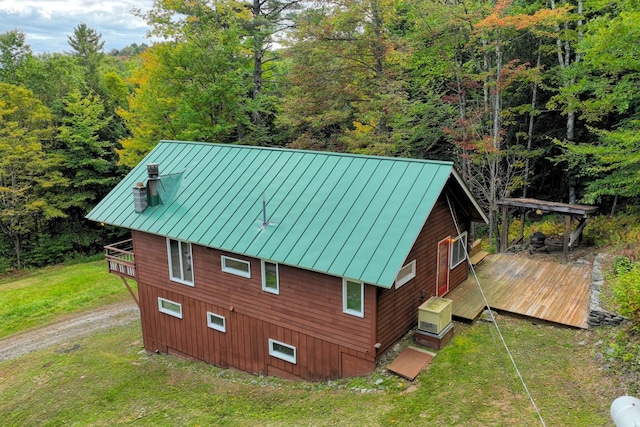 view of property exterior featuring a wooden deck and a lawn