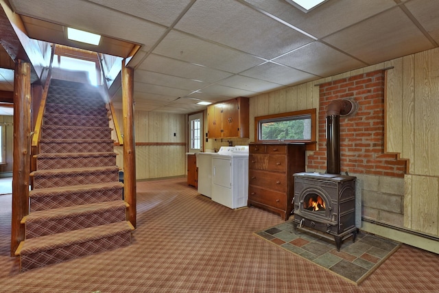 basement with a wood stove, a drop ceiling, a healthy amount of sunlight, and light colored carpet