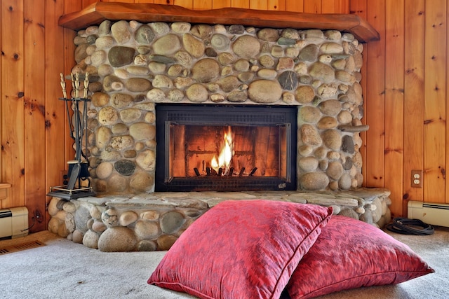 details with a stone fireplace, wood walls, carpet flooring, and a baseboard heating unit