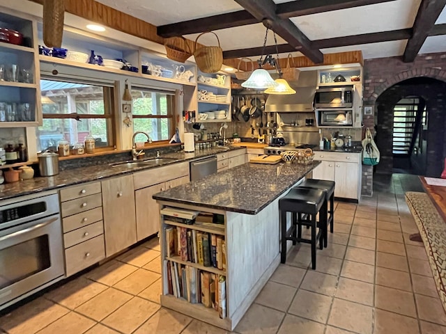 kitchen featuring a kitchen island, stainless steel appliances, sink, hanging light fixtures, and a breakfast bar area