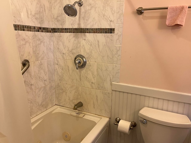 bathroom with tiled shower / bath combo and toilet