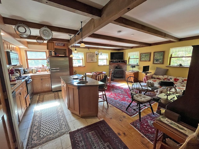 kitchen featuring light hardwood / wood-style flooring, a kitchen island with sink, appliances with stainless steel finishes, and a healthy amount of sunlight